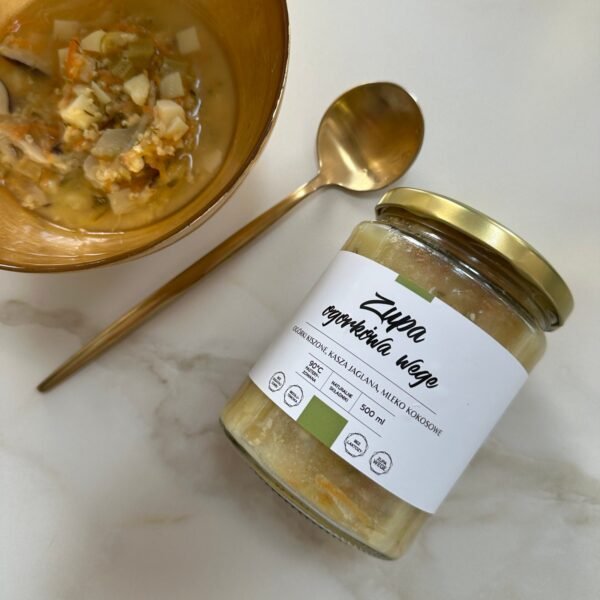 Zupa ogórkowa wege Juice Concept w eleganckim, minimalistycznym słoiku, przygotowana na bazie naturalnych ogórków kiszonych, warzyw korzeniowych i kaszy jaglanej. Na zdjęciu widoczna jest gęsta, kremowa zupa o jasnym, lekko zielonkawym kolorze, z wyraźnymi kawałkami ziemniaków, marchewki oraz świeżym koperkiem na wierzchu. Konsystencja zupy podkreśla jej sycący, ale jednocześnie lekki charakter, idealny dla osób dbających o zdrowie jelit i trawienie. Produkt prezentowany jest w estetyce clean, charakterystycznej dla marki premium – czyste tło, naturalne kolory i prostota kompozycji podkreślają jakość oraz brak sztucznych dodatków. Zupa ogórkowa wegańska to funkcjonalny posiłek wspierający mikrobiom jelitowy dzięki obecności naturalnych probiotyków z kiszonych ogórków. Dodatkowo kasza jaglana działa przeciwzapalnie i wspomaga regenerację układu pokarmowego. To gotowa zdrowa zupa w słoiku, idealna jako szybki, wartościowy posiłek dla osób żyjących w biegu, które chcą zadbać o odporność, równowagę organizmu i codzienną energię. Zdjęcie oddaje filozofię świadomego odżywiania, naturalności i funkcjonalnego podejścia do zdrowia.