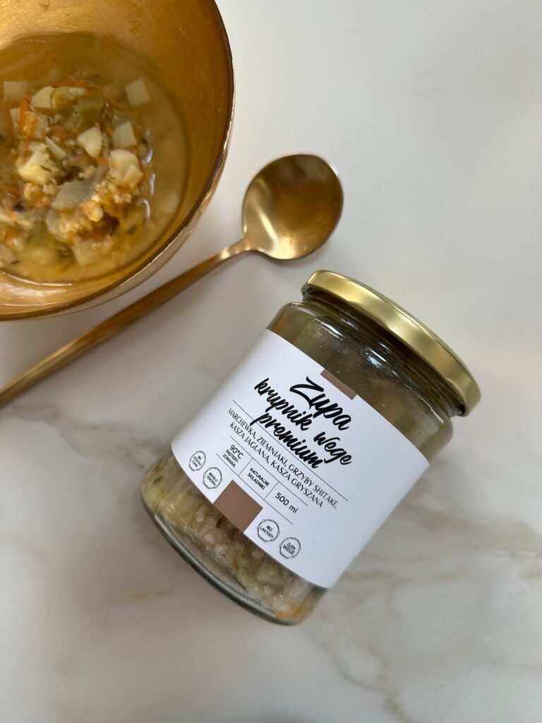 Zupa krupnik wege w słoiku Juice Concept – naturalna, roślinna zupa funkcjonalna przygotowana z kaszy jaglanej i gryczanej, świeżych warzyw korzeniowych oraz grzybów shiitake. Na zdjęciu widoczna jest klarowna, gęsta zupa o ciepłym, złocistym kolorze, z kawałkami marchewki, ziemniaków i zielonej natki pietruszki. Produkt prezentowany jest w estetycznym, minimalistycznym słoiku, charakterystycznym dla marki premium. Zupa wygląda świeżo, lekko i odżywczo, podkreślając naturalny skład bez sztucznych dodatków, glutenu i laktozy. To zdrowa zupa roślinna wspierająca jelita, trawienie i mikrobiom, idealna jako lekki, ale sycący posiłek na co dzień. Kompozycja zdjęcia oddaje filozofię clean eating, funkcjonalnego odżywiania i świadomego dbania o organizm. Krupnik wegański w tej formie to nowoczesne podejście do tradycyjnej kuchni – wygodne, gotowe rozwiązanie dla osób dbających o zdrowie, energię i równowagę organizmu. Idealny wybór dla osób poszukujących naturalnych produktów premium, które wspierają regenerację, stabilny poziom energii i komfort trawienny.